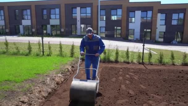 Homem trabalhando duro no jardim com rolo de solo. Movimento gimbal para trás — Vídeo de Stock