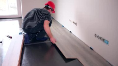 Tamir ve ev konsepti. Erkek işçi ahşap döşeme kuruyor