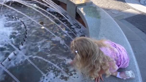 Piccola ragazza bionda in abito giocare con acqua di fontana in estate. Colpo palmare — Video Stock