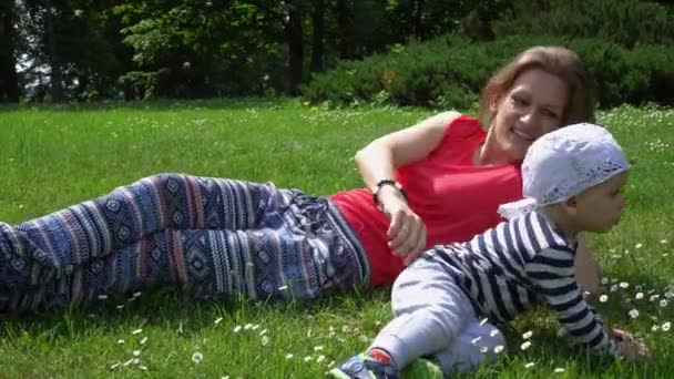 Heureuse mère gaie avec un petit fils couché sur la prairie et montrer le ciel doigt — Video