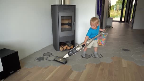 Helper jongen schone vloer met hoover thuis. Schattig kind met grote stofzuiger — Stockvideo