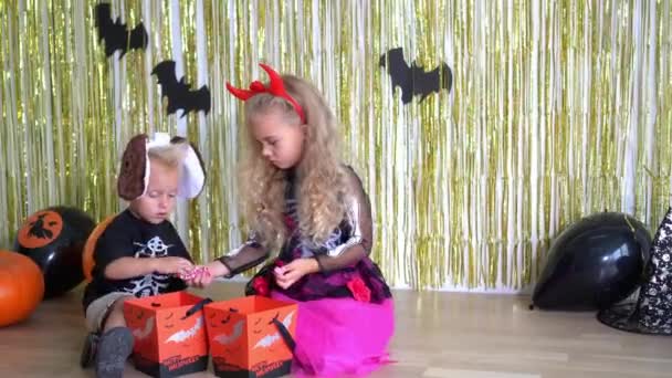 Очаровательные дети лучшие друзья делятся сладостями на Хэллоуинской вечеринке — стоковое видео
