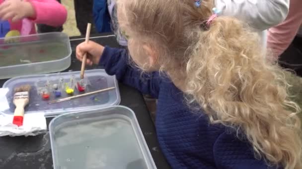 Bonita niña rubia pintar en la tecnología de agua ebru. Gimbal tiro de movimiento — Vídeos de Stock