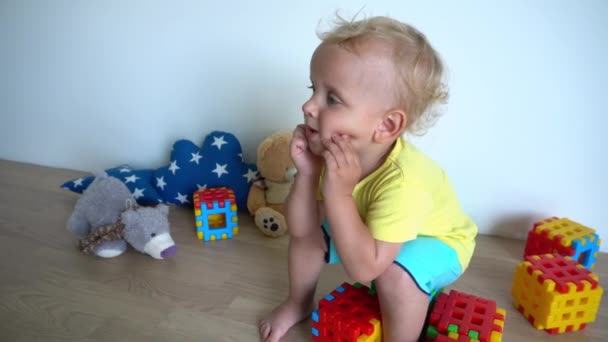 Niño soñador sentado en bloques de colores en casa. Movimiento del cardán — Vídeos de Stock