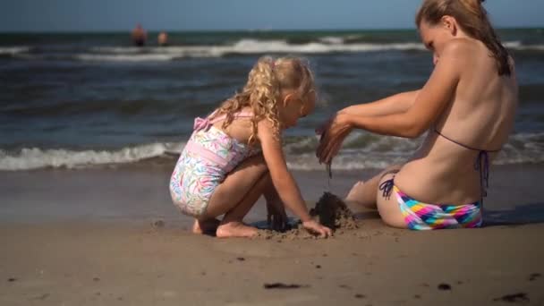 Família meninas filha e mãe em maiôs construir molhado castelo de areia na costa do mar — Vídeo de Stock