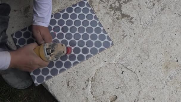 Obrero de la construcción cortar agujeros en baldosas utilizando una amoladora angular con corona de diamante — Vídeo de stock
