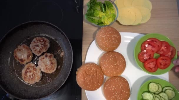Frying meatballs in a pan and burger ingredients. Vegetables bun and cheese — 图库视频影像