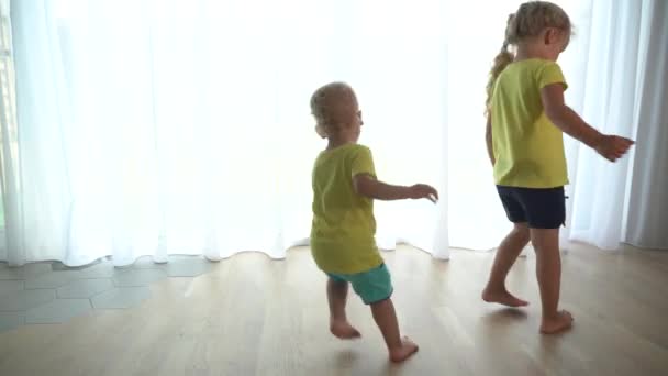 Klein zuster meisje en jong aanbiddelijke broer draaien rond in huis — Stockvideo