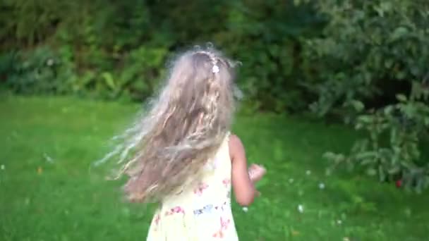 Bonne petite fille courant dans le jardin et se cachant entre les arbres — Video