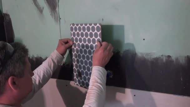 Tiler man apply wall tile around hot and cold water pipes in bathroom. — Stock Video