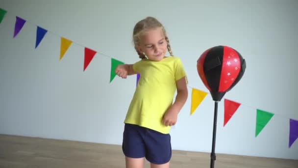 Criança caucasiana batendo saco de perfuração. Menina brincalhão ativa se divertir em casa — Vídeo de Stock