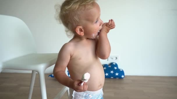 Adorable baby boy face is smeared with ice cream. Child in diapers eating sweets — Stok video