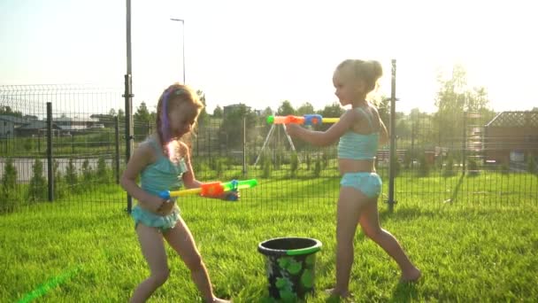 Дівчата, що сміються, найкращі друзі з купальниками, сплющуються з водяними рушницями. Повільний рух . — стокове відео