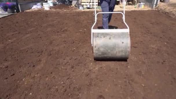 Trabajador duro trabajando en el jardín con rodillo de suelo. Movimiento de gimbal hacia atrás — Vídeos de Stock