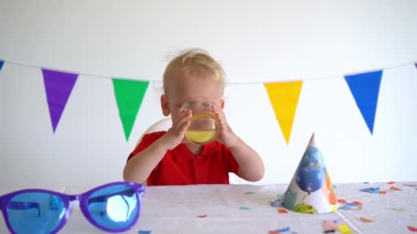 Niño bebiendo jugo de naranja. Cumpleaños después de la fiesta. Movimiento de gimbal hacia adelante — Vídeo de stock