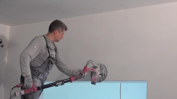 Skilled man with grinder machine polishing wall at new apartment — 비디오