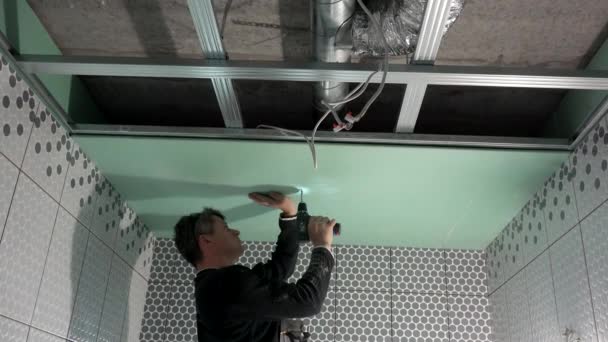 Lavoratore sta fissando cartongesso ai profili del soffitto con cacciavite. palmare — Video Stock