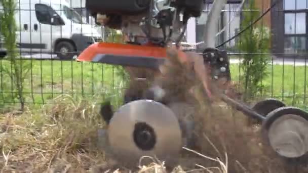 Cultivator blades plowing soil with grass at townhouse yard. Gimbal motion — 비디오