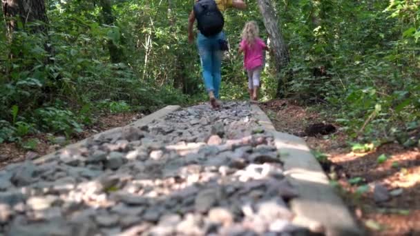 Mulher com menina caminhe pelo caminho áspero com pequenas pedras. Massagem nos pés — Vídeo de Stock