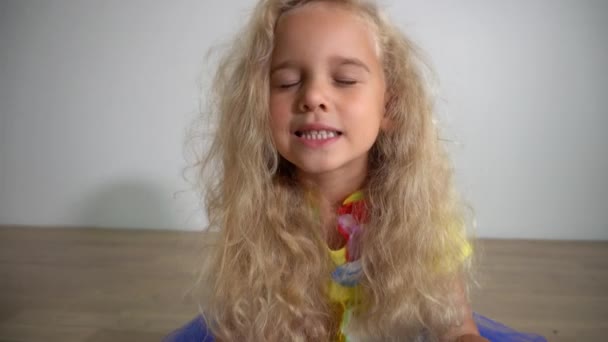 Τετράχρονο κορίτσι χαλαρώνει διαλογιζόμενο στο πάτωμα του δωματίου. Ξανθά σγουρά μαλλιά παιδί — Αρχείο Βίντεο