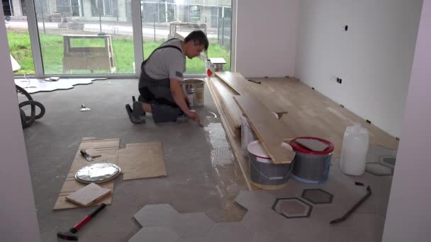 Skilled worker apply glue with trowel on floor for floorboard laying — 비디오