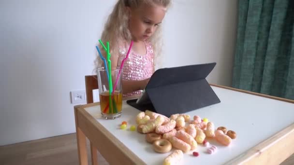 Little girl sit play using a computer tablet. Various sweets. Gimbal movement — Stock Video