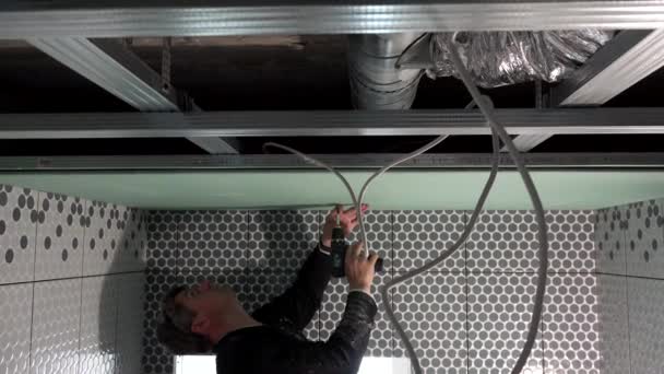 Trabalhador qualificado está fixando drywall ao teto com chave de fenda acumulador — Vídeo de Stock