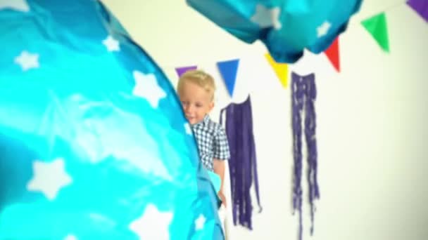 Glücklicher zweijähriger Junge feiert zweiten Geburtstag sitzend auf Stuhl mit Luftballon — Stockvideo