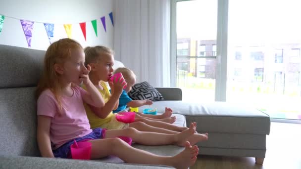 Niños cariñosos comiendo palomitas de maíz bebiendo jugo y viendo películas de dibujos animados — Vídeos de Stock