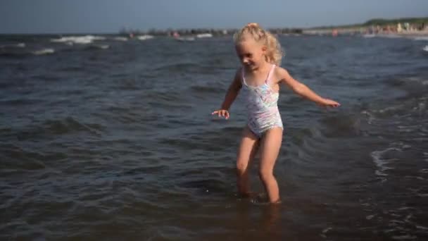 Šílená dívka tančí a kopat mořské vlny s nohama. dítě stříkající vodu — Stock video