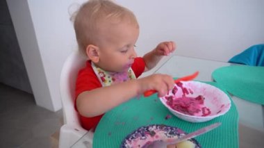 Funny caucasian boy eating beetroot soup straight from plate