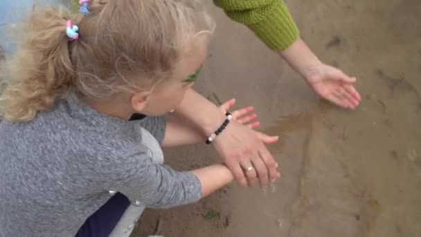 Madre lavando las manos de su hija en el agua del lago. Movimiento del cardán — Vídeo de stock