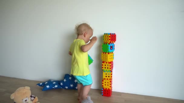 Προσεκτικό αγόρι παιδί κτίριο πύργο από πολύχρωμα μπλοκ στο σπίτι. Λαμπερή κίνηση — Αρχείο Βίντεο