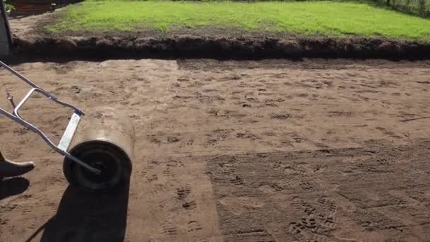 Compattazione del terreno con rullo dopo la semina prato in cortile. Colpo di moto palmare . — Video Stock