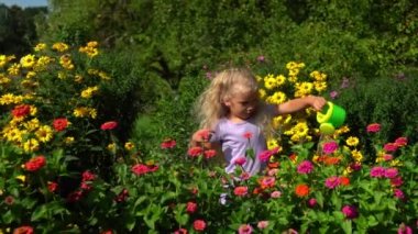 Plastik sulama kutusuyla güzel bir kız yaz bahçesinde çiçekleri sular.