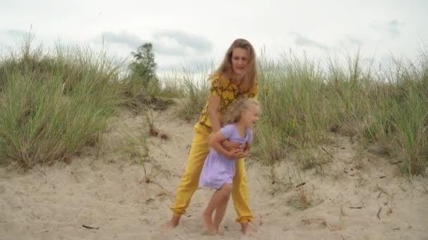 Maman tourne sa fille blonde autour d'elle. Les filles de la famille active s'amusent dans les dunes — Video