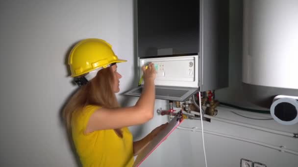 Ingeniera mujer con casco comprobando los datos técnicos de los equipos del sistema de calefacción — Vídeos de Stock