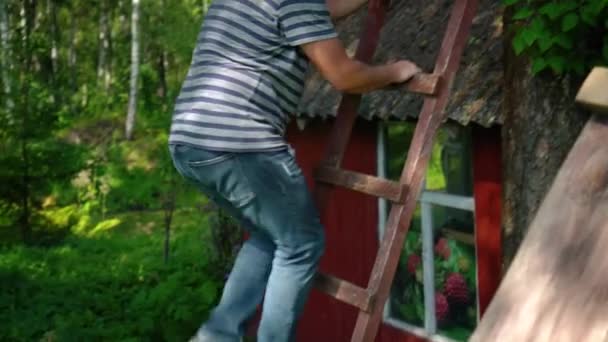 Dikke man klimmend op hoge houten ladder buiten. Camera omhoog kantelen — Stockvideo