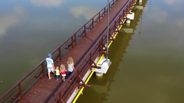 Familie spaziert entlang Holzbrücke über den See. Drohnenschuss aus der Luft. — Stockvideo