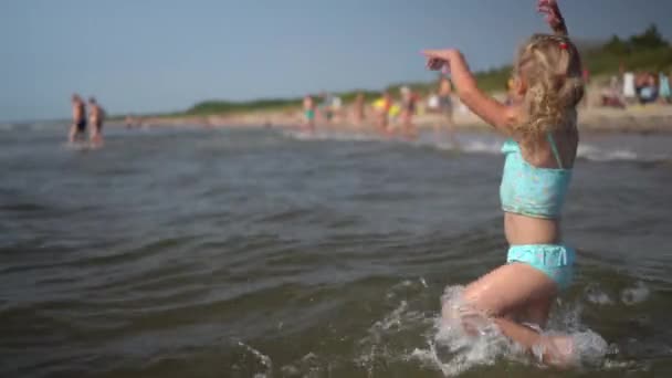 Активний грайливий маленька дівчинка танцює по морських водних хвилях. Забавна дитина — стокове відео