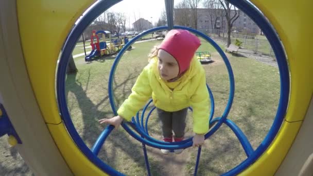 Menina ativa escalar através de buracos playground redondo. Tiro de movimento Gimbal — Vídeo de Stock