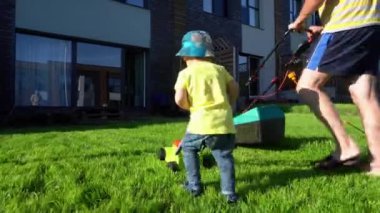 Family boys father and son cut mow lawn grass in private yard. Gimbal movement