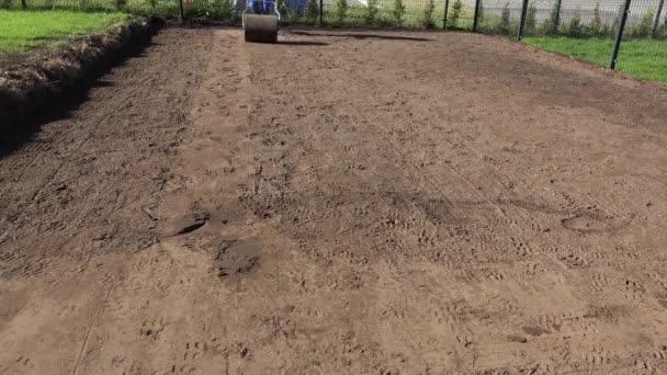 Hombre cualificado con rodillo de tierra. Preparación del terreno para la siembra de césped — Vídeos de Stock