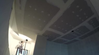 İnşaat işçisi apartmanın tavanını alçıyla temizliyor. Zaman Uygulaması