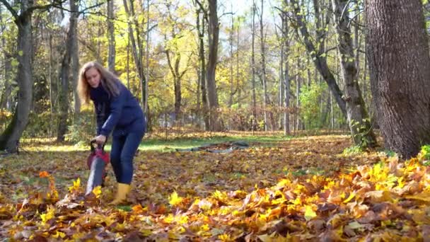 Непослушная девочка заставляет листья драться с матерью-садовницей на осеннем дворе — стоковое видео