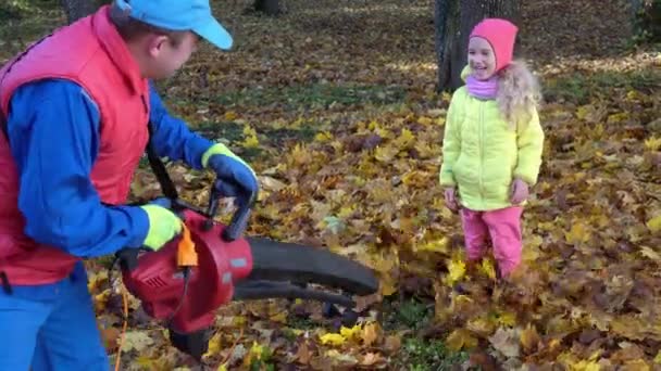 Playful man blowing leaves at his little girl daughter standing in garden yard — Stockvideo
