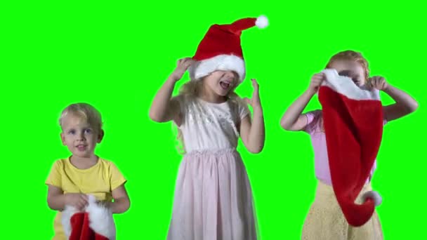 Неслухняні діти грають з різдвяними шапками на голові. фон зеленого екрану — стокове відео