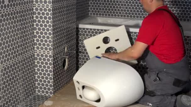 Plumber man add special rubber sheet on wall. Preparation for hang toilet bowl — Wideo stockowe