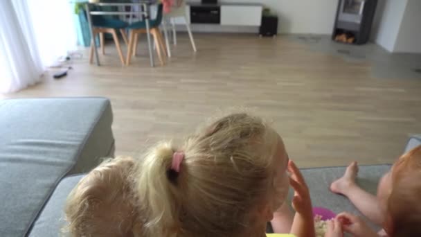 Malé děti jíst popcorn a sledovat kreslený film na domácí kino — Stock video