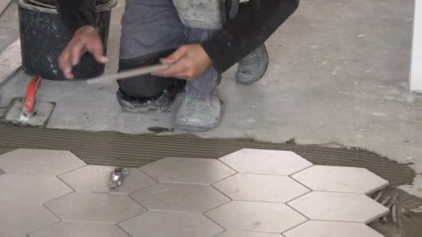 Arbeiter verlegt sechseckige Steinmassenfliesen auf dem Boden. — Stockvideo
